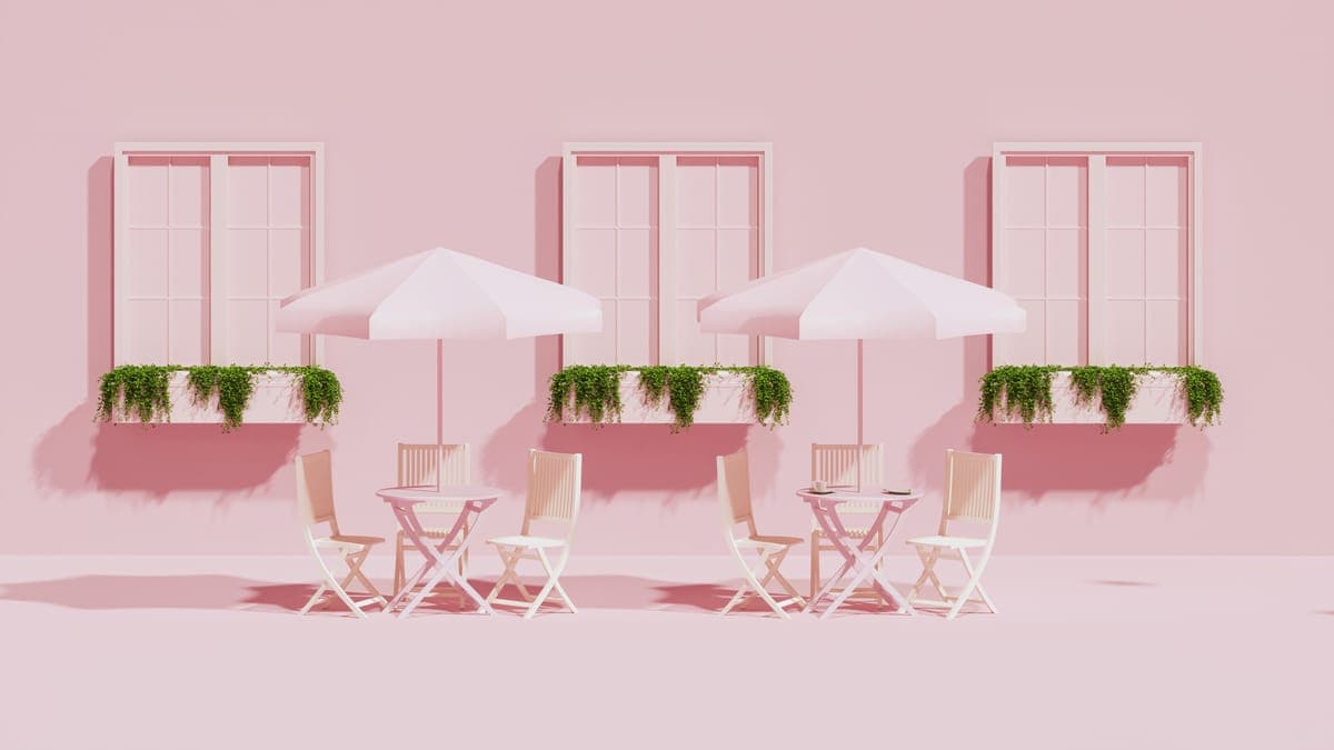 Pink cafe front with outdoor tables, umbrellas and window flower boxes