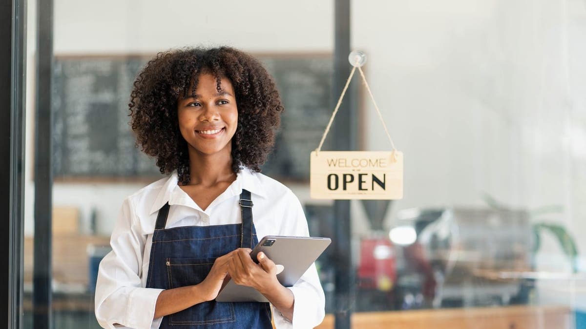 Cafe owner holding a tablet and smartphone behind her counter