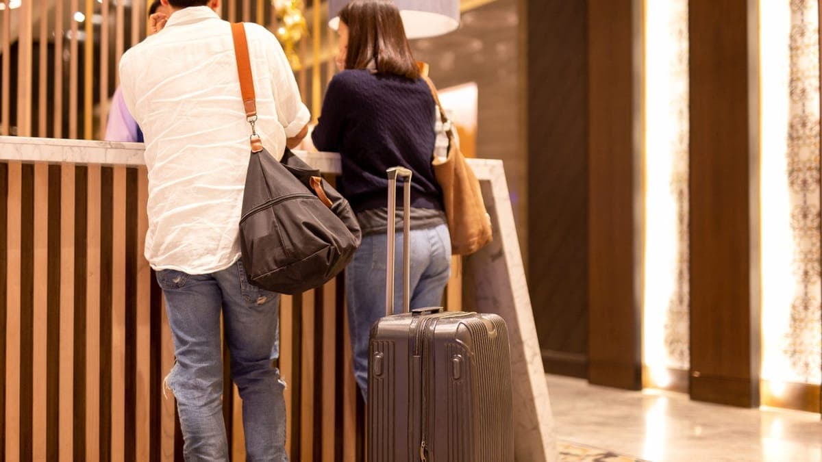 Couple with a suitcase checking in at a hotel reception desk