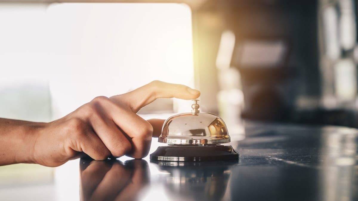 Hand ringing the bell on a hotel reception desk