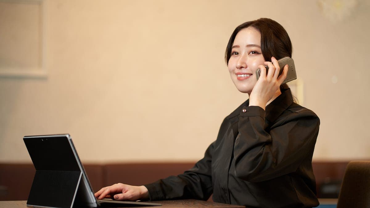 Restaurant manager on the phone while typing on a tablet at a dining table